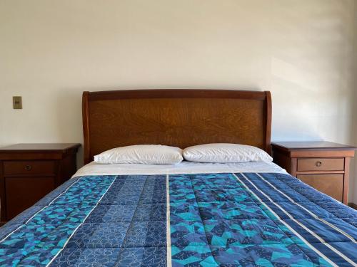 a bed with two nightstands and a blue quilt at BUIN CENTRO Departamento in Maipo