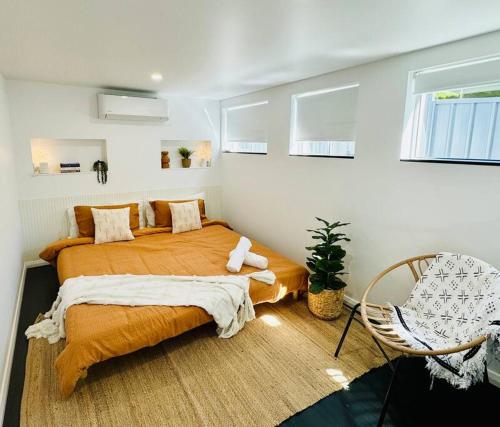 a bedroom with a large bed and a chair at Luxury beachside sanctuary in Adamstown