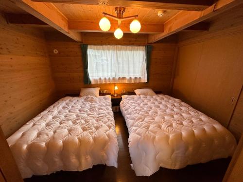 2 camas grandes en una habitación con ventana en 舞鶴ふるるファームコテージ en Maizuru