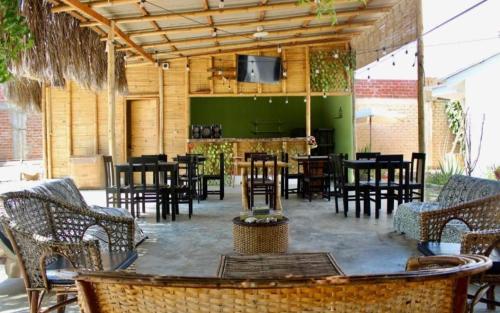 a restaurant with tables and chairs and a television on a patio at Pascana Casa Playa in Máncora