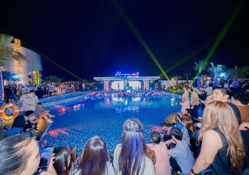 a crowd of people standing around a swimming pool at night at Pentacity Hotel Balikpapan in Balikpapan
