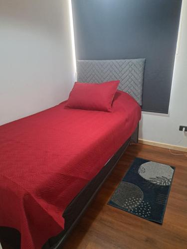 um quarto com uma cama vermelha e uma almofada vermelha em Depto. Playa La Herradura Coquimbo em La Serena