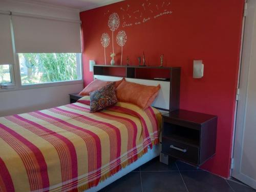 um quarto com uma cama e uma parede vermelha em LAS LOMAS em Miramar