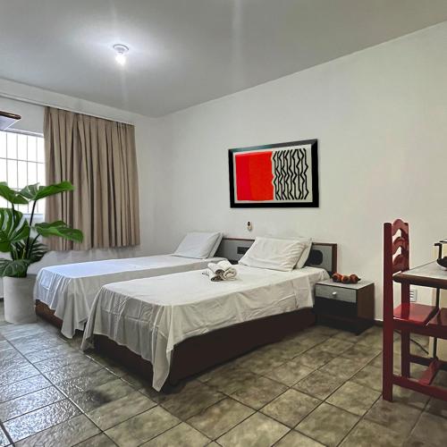 a bedroom with two beds and a painting on the wall at Malakoff Residence in Recife