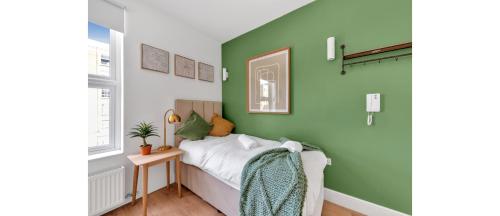 a bedroom with green walls and a bed with a table at Cozy and Lovely Studio - Close to everything! in London