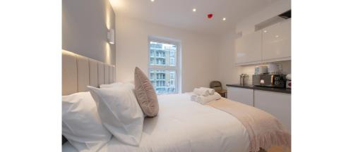 a white bedroom with a large bed with white pillows at Dainty Studio Apartment Close to Everything in London