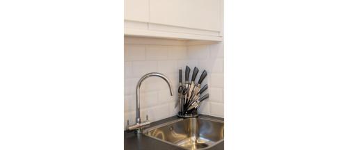 a kitchen sink with utensils in a holder at Dainty Studio Apartment Close to Everything in London