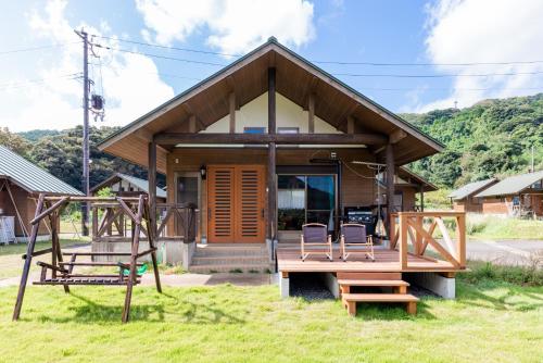 a small house with two chairs and a swing at 舞鶴ふるるファームコテージ in Maizuru