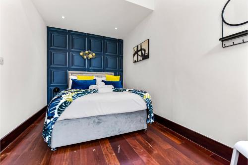 Comfortable 3 Bedroom Apartment in Greater London في Hanwell: غرفة نوم مع سرير مع اللوح الأمامي الأزرق