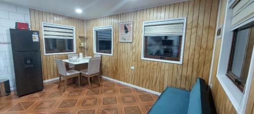 Zimmer mit einer Holzwand, einem Tisch und einem Kühlschrank in der Unterkunft cabaña los teros in Coihaique