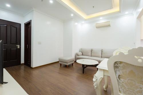 a white living room with a couch and a table at The Peninsula Haiphong in Hai Phong