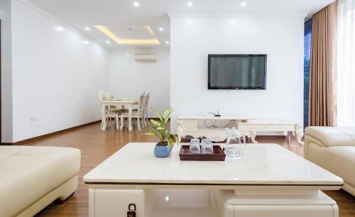 a white living room with a couch and a tv at The Peninsula Haiphong in Hai Phong
