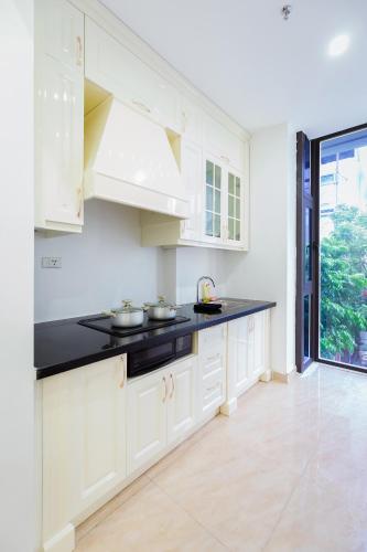 a kitchen with white cabinets and a black counter top at The Peninsula Haiphong in Hai Phong