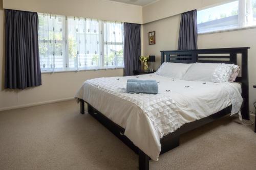 a bedroom with a large bed with white sheets and windows at Glenview home in Hamilton