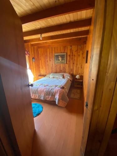 a bedroom with a bed in a wooden cabin at Casa Licanray in Licán Ray