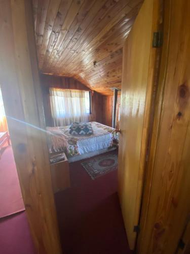 a small bedroom with a bed in a wooden cabin at Casa Licanray in Licán Ray