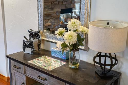 a table with a vase of flowers and a mirror at Parkland301 Sunlit 2,000 ft² Penthouse with Mtn View in Canmore