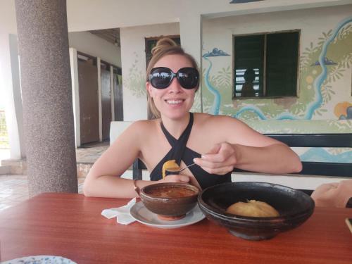 a woman sitting at a table with a bowl of food at Afiki in Ankwanda