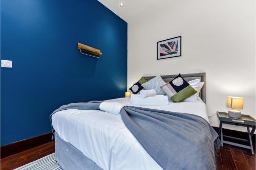 - une chambre avec un mur bleu et un lit dans l'établissement Lovely 2-bedroom rental unit in Greater London, à Hanwell