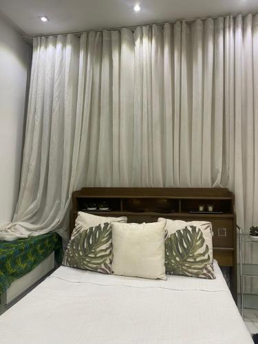 uma cama com lençóis brancos e almofadas num quarto em Flat suítes mobiliados central em Araguaína