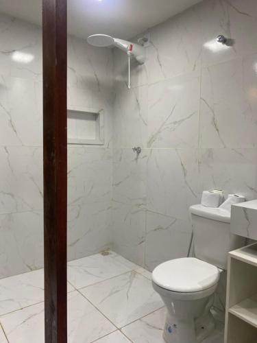 a white bathroom with a toilet and a shower at Flat suítes mobiliados central in Araguaína