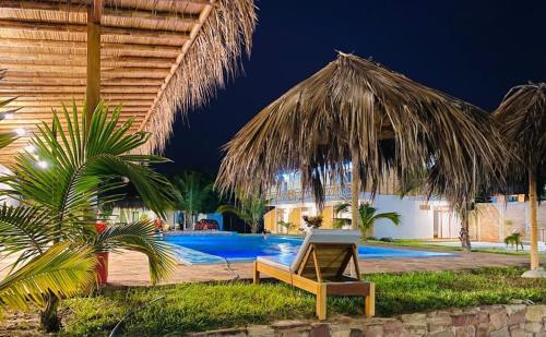 a resort with a chair and a swimming pool at night at Pascana Casa Playa in Máncora
