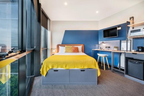 a bedroom with blue walls and a bed with a yellow blanket at Together Co-Living Melbourne in Melbourne