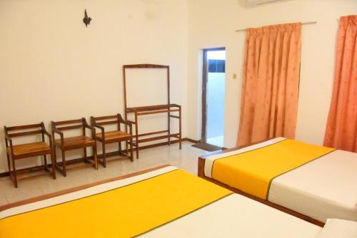 a bedroom with two beds and chairs and a mirror at Yellow Birds Resort in Anuradhapura