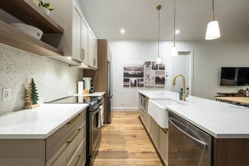 a large kitchen with white counter tops and wooden floors at Chalet TERRE en harmonie avec la nature, Tremblant in Lac-Superieur