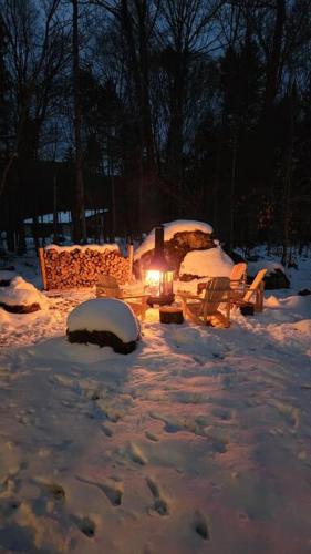 a table and chairs in the snow with a light at Chalet TERRE en harmonie avec la nature, Tremblant in Lac-Superieur