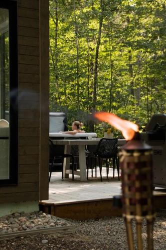 a woman sitting at a table on a patio at Chalet TERRE en harmonie avec la nature, Tremblant in Lac-Superieur