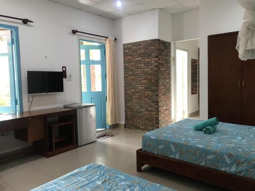 Dormitorio con cama, escritorio y TV en Nhat Quang Bungalow, en Mui Ne