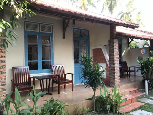 a house with two chairs and a table on a patio at Nhat Quang Bungalow in Mui Ne