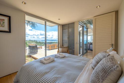 a bedroom with a bed with a view of the ocean at Nikau Estate, Oneroa - Be My Guest in Matiatia Bay