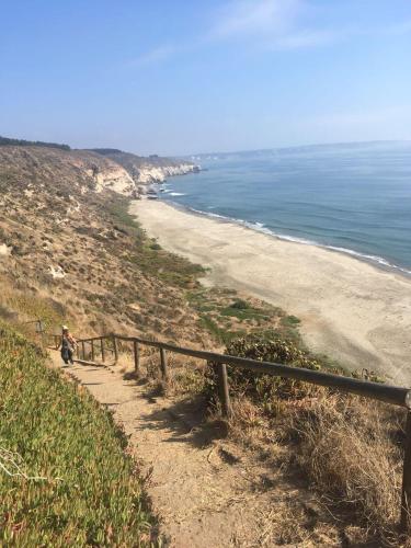 a person sitting on a path next to a beach at Cabaña Los Laureles in Maitencillo