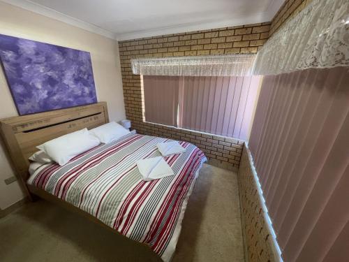 a small bedroom with a bed and a window at Puggle Palace, 21A Bower Street in Jurien Bay
