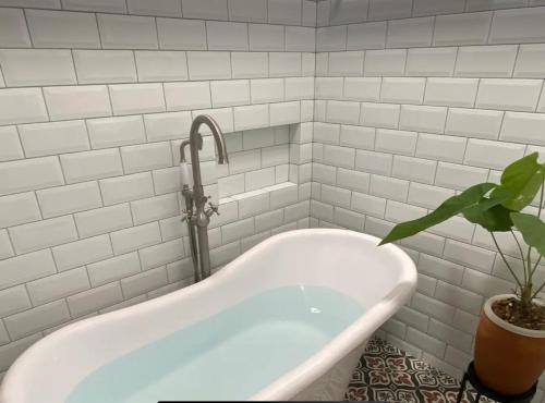 a bath tub with a faucet and a plant in a bathroom at The Joglo Villa in Bandung