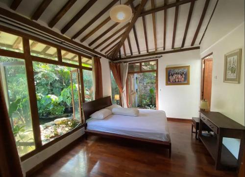 a bedroom with a bed and a desk and windows at The Joglo Villa in Bandung