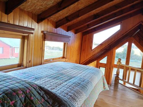 1 dormitorio con 1 cama en una habitación con ventanas en cabañas los maites, en Chonchi