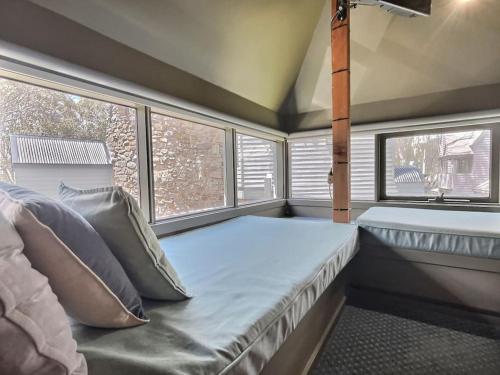 Un dormitorio con una cama y dos ventanas. en Glacier Chalet, en Dinner Plain