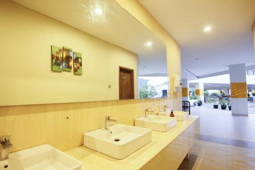 a bathroom with two sinks and two mirrors at Raja Hotel Kuta Mandalika Resort & Convention in Kuta Lombok
