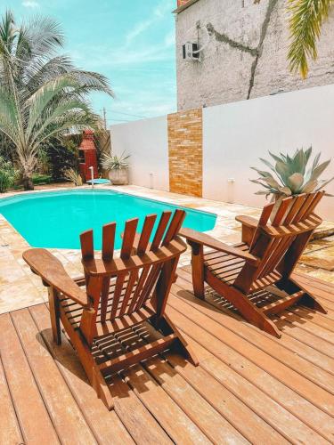 dwa drewniane krzesła siedzące na tarasie obok basenu w obiekcie Villa Fortal Preá w mieście Preá