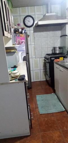 a small kitchen with a stove and a clock on the wall at Departamento casa en arica in Arica