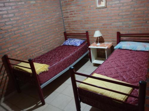 two beds in a room with a brick wall at los nidos habitaciones in Villa Cura Brochero