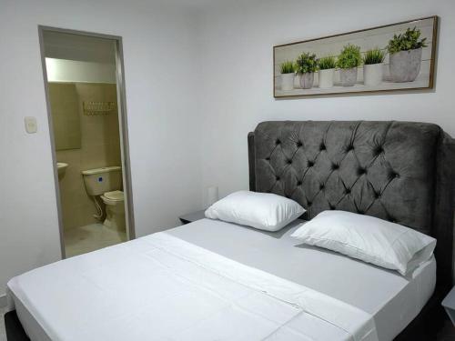 a bedroom with a white bed with a gray headboard at Apartamento de 3 HABITACIONES en Bucaramanga in Bucaramanga