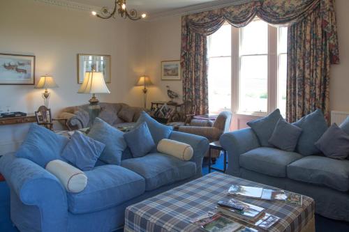 a living room with blue furniture and a blue couch at Whitehouse Country House in Saint Boswells