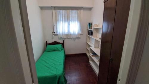 a small bedroom with a green bed and a window at Departamento Plaza Colon in Mar del Plata