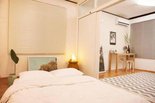 a bedroom with a bed and a window with blinds at Good In Beach_ Lovely Place in Pyoseon (Haevichi) in Seogwipo