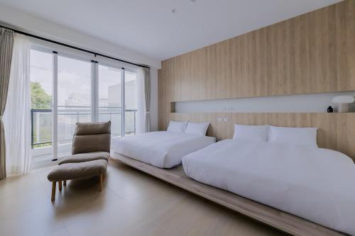 a bedroom with two beds and a chair at Terumahouse 照間 民宿編號2016號 in Taitung City