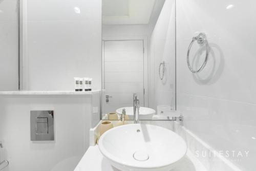 a white bathroom with two sinks and a mirror at Adorable Bright Villa in Residential Community in Dubai